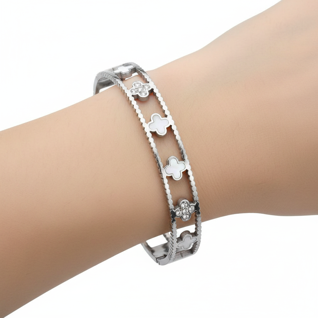 Woman's wrist wearing stainless steel quatrefoil hinged bangle bracelet, side profile view, white background