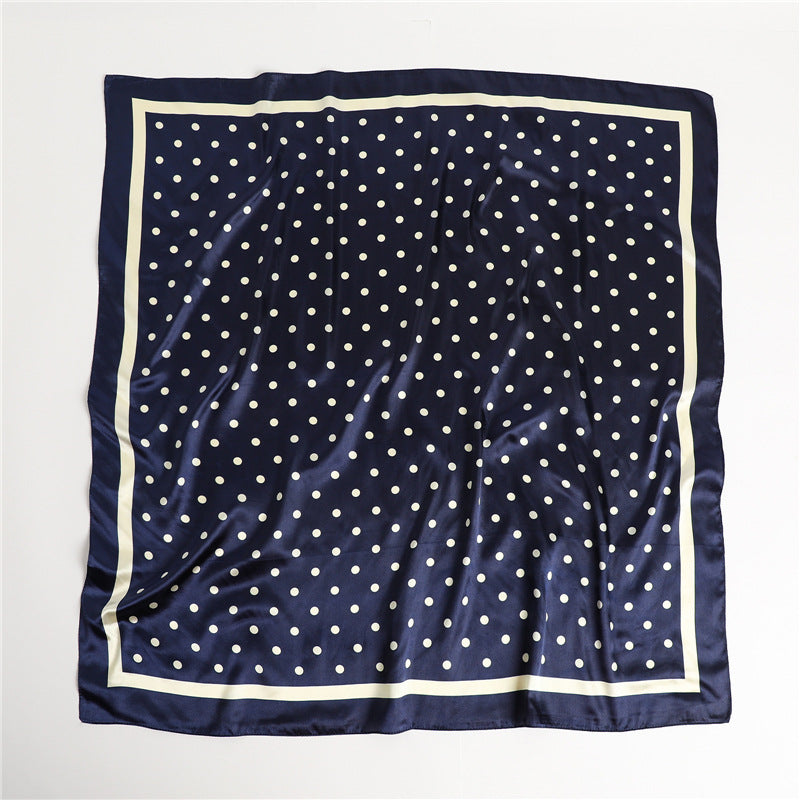 Navy blue polka dot silky square scarf close-up showing fabric texture and cream border