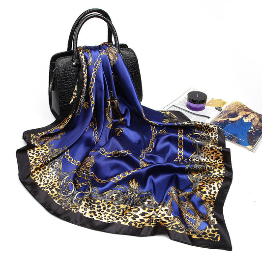 Navy blue leopard chain print silk-feel square scarf draped over black leather handbag