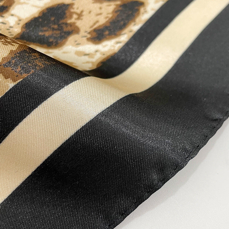 Leopard print polyester satin fabric close-up showing rich brown and black animal print pattern