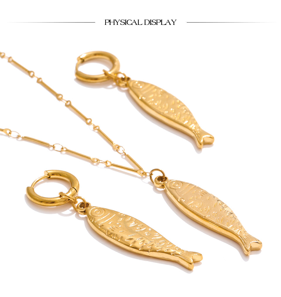 Model wearing gold fish pendant necklace and earrings