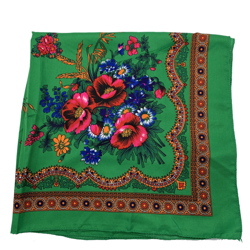 Close-up detail of green floral scarf showing ornamental border and fabric texture