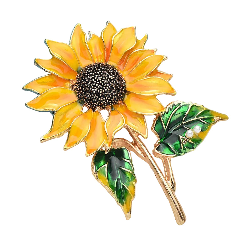 Sunflower enamel brooch with yellow petals, dark crystal center, and green leaf accents on white background