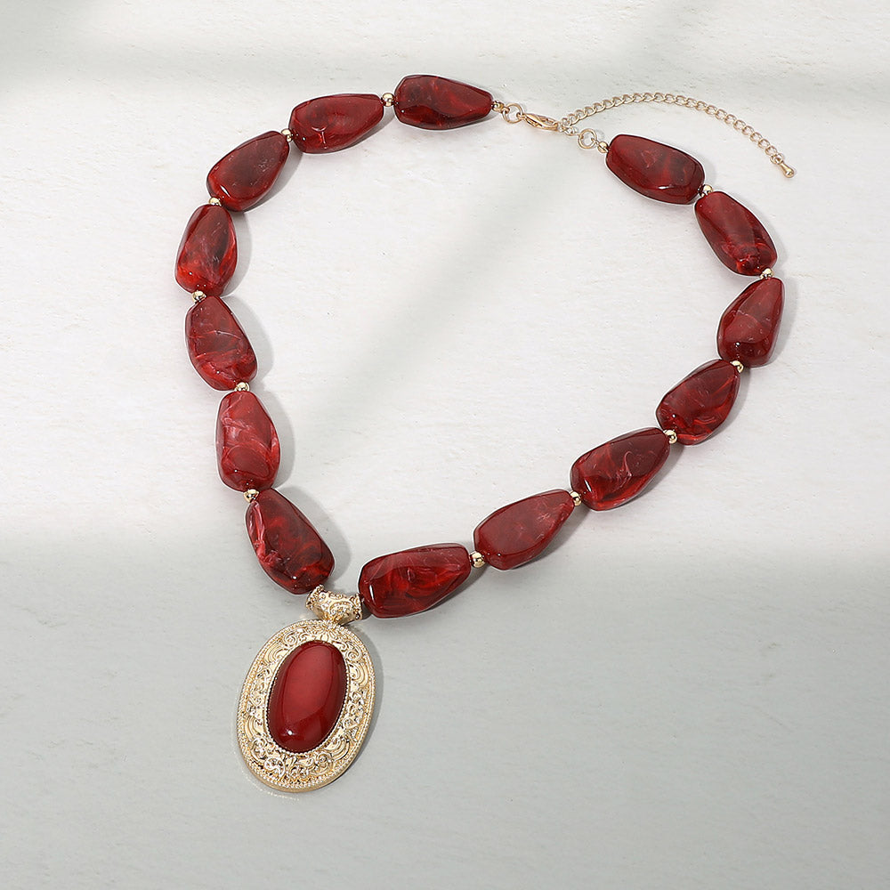 Crimson beaded statement necklace with gold filigree pendant - product shot on white background