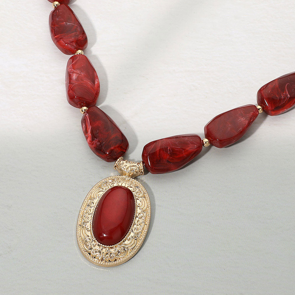 Crimson beaded statement necklace - close-up of gold filigree pendant detail