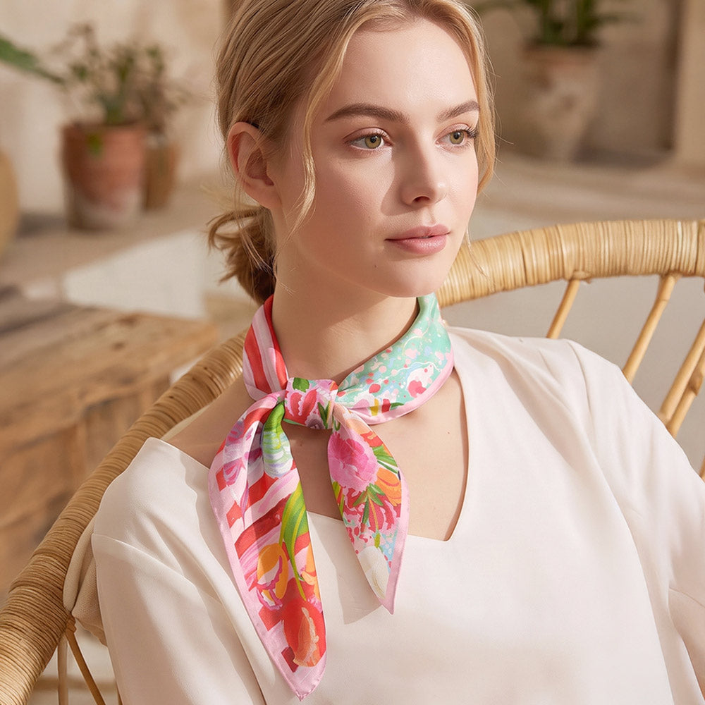 Woman wearing painterly floral square scarf tied at the neck over a white blouse