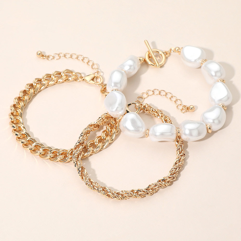 Baroque pearl station bracelet and twisted gold chain bracelet on white background
