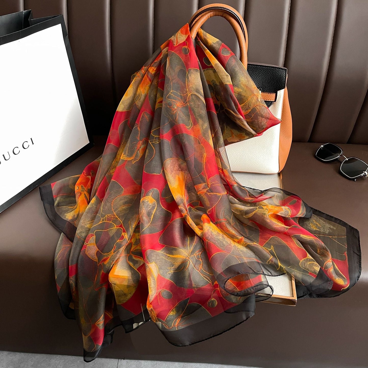 Autumn floral silk scarf in red, amber and charcoal — draped over designer bag flat lay