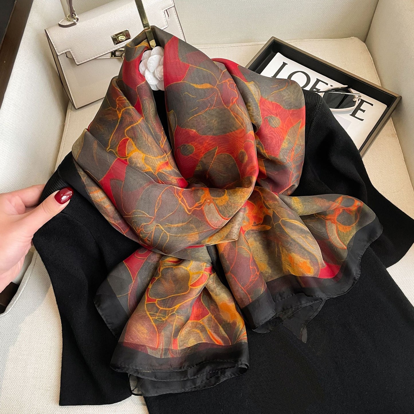 Silk-feel floral wrap scarf in crimson and gold tones — styled over black outfit detail