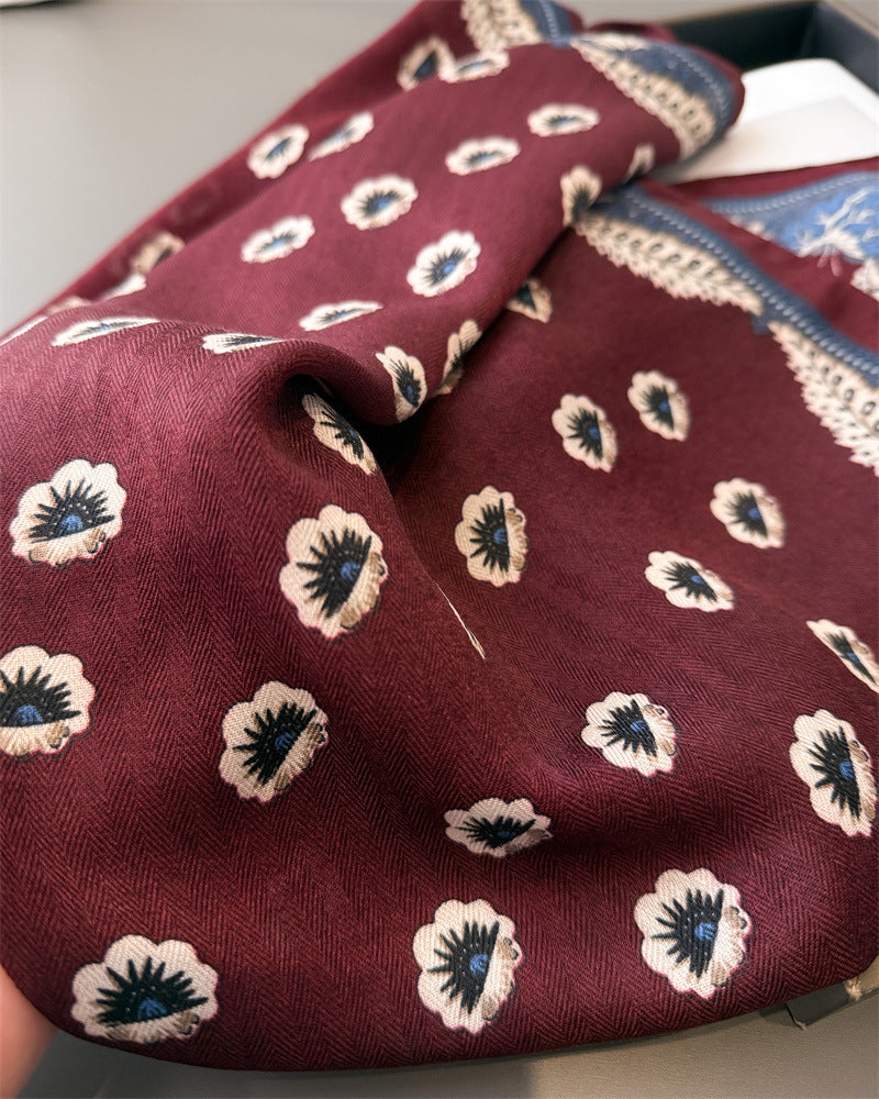 Woman wearing burgundy floral paisley square scarf folded into triangle and tied at neck over white button-down shirt