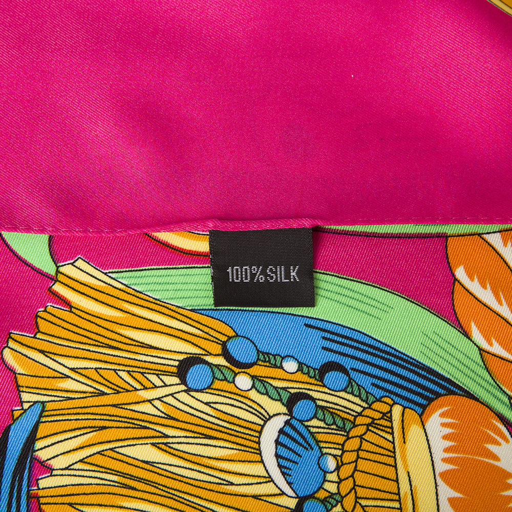 Close-up of fuchsia silk scarf with green and blue ribbon, gold chain and star medallion print