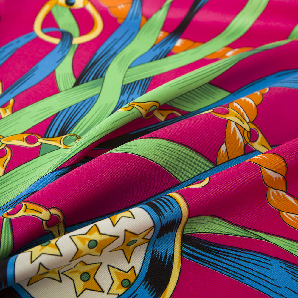 Close-up of fuchsia silk scarf showing gold chain link and circular medallion detail