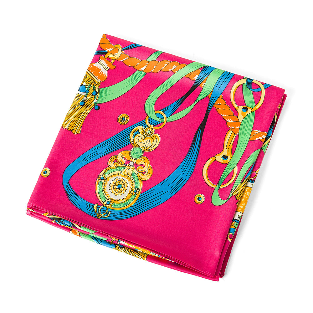 Close-up of fuchsia silk scarf with orange rope twist, blue ribbon and gold chain hardware