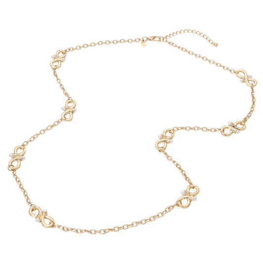 Woman wearing long gold infinity station necklace with pearl accents over a grey blouse