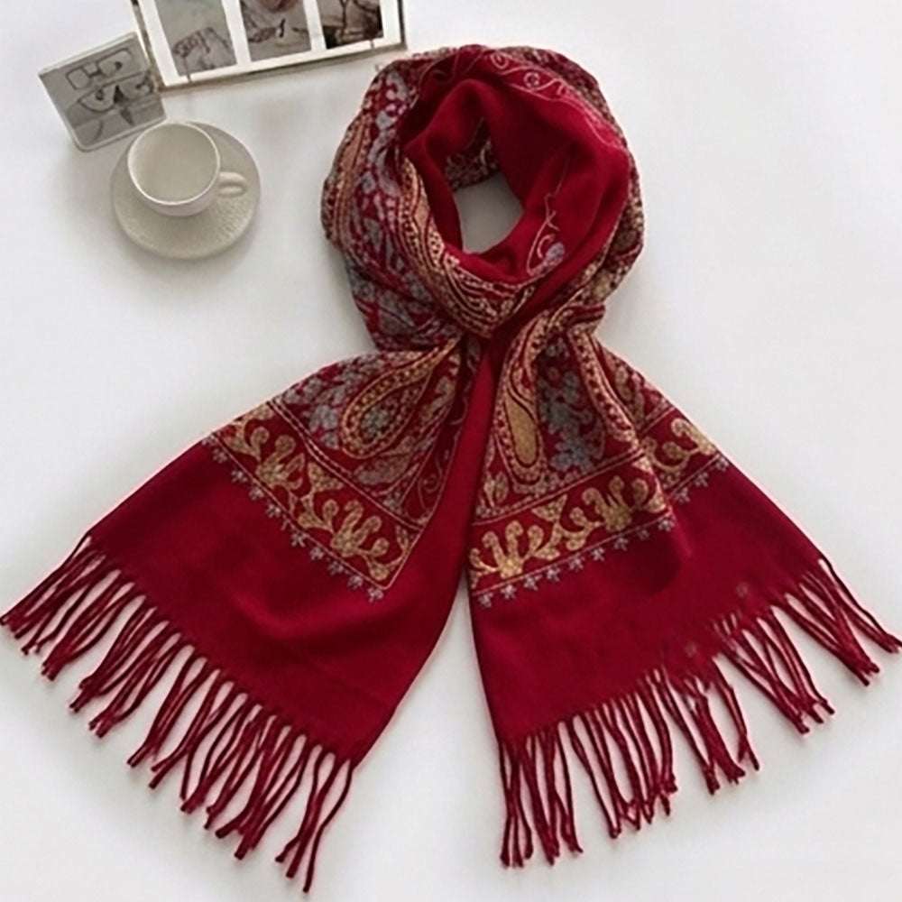 Woman wearing crimson paisley embroidered scarf wrap looped around neck, styled with white sleeveless top