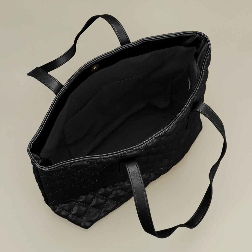 Interior of black quilted tote bag showing spacious open compartment and inside slip pocket