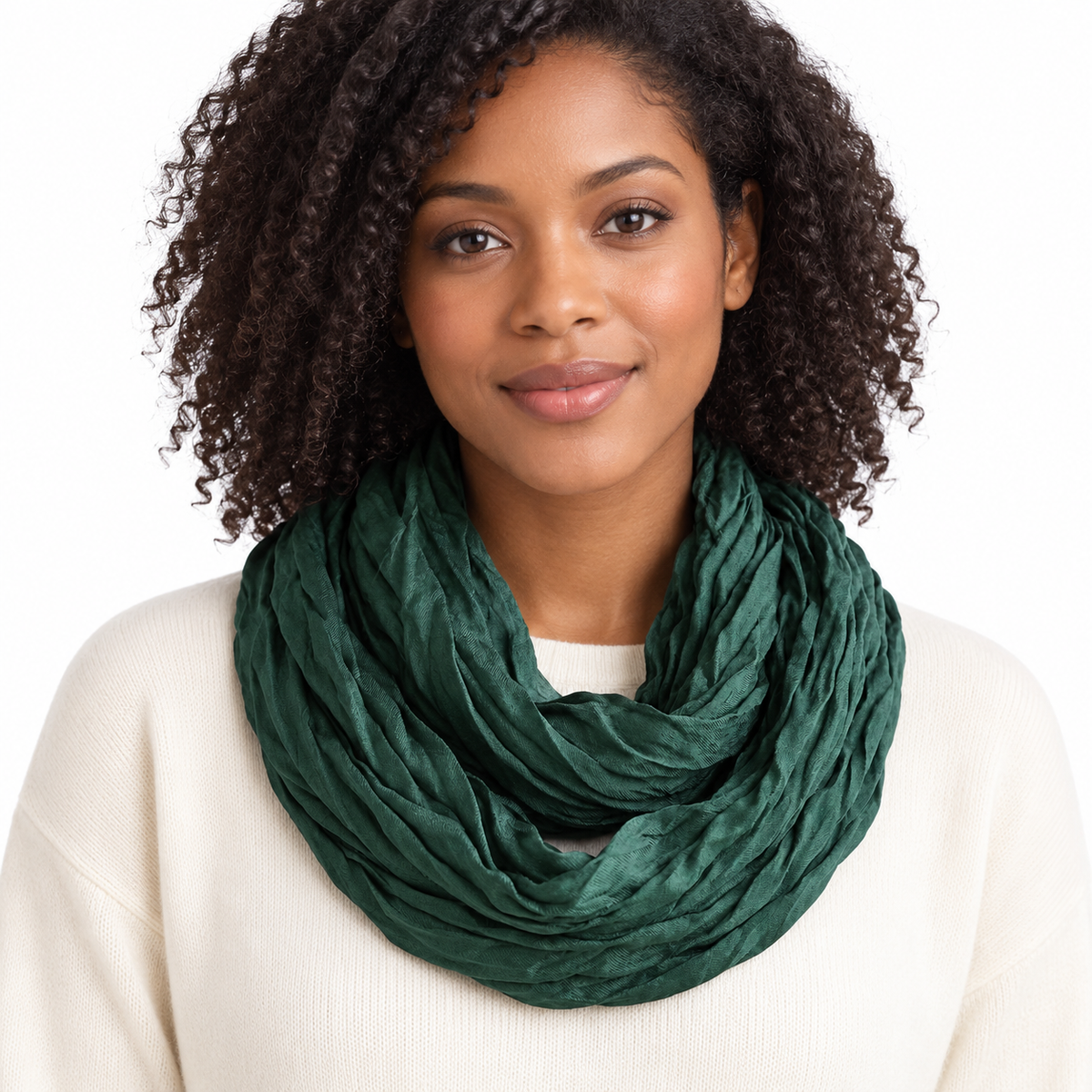 Black woman with curly hair wearing deep forest green crinkle infinity scarf doubled at the neck over a cream sweater