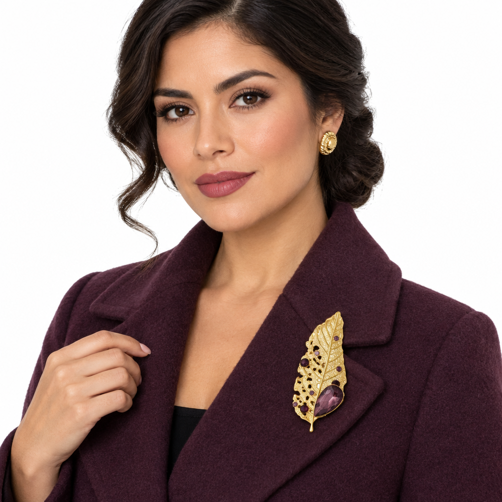 Front view lifestyle shot of the gold leaf brooch pinned to a wool coat lapel, worn by a Hispanic woman, white background