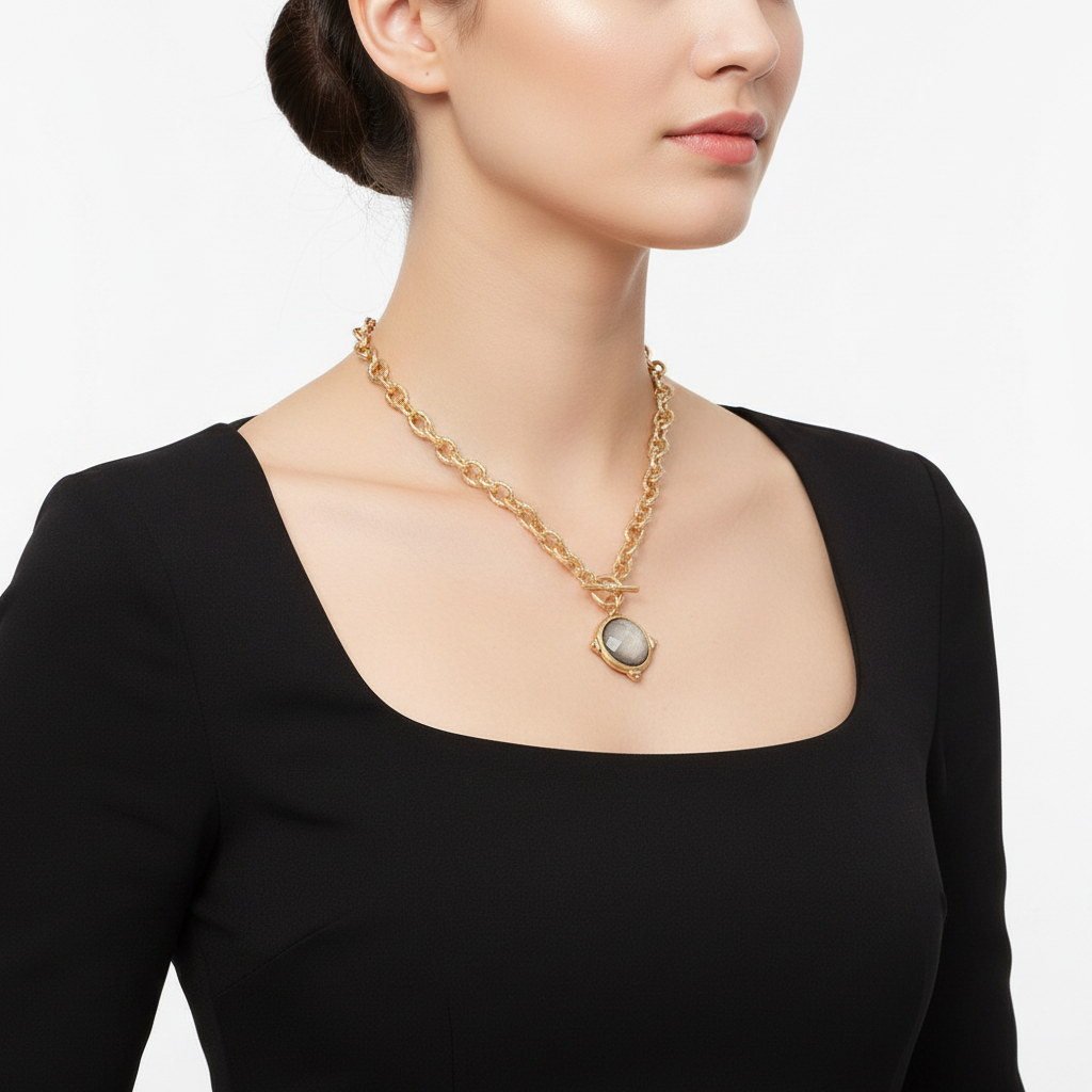 Model wearing gold tone rope chain toggle necklace with grey stone pendant, side view showing toggle clasp, black dress, white background
