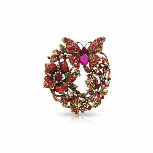 Front product view of antique gold-tone butterfly floral wreath brooch with red rhinestones and magenta accent